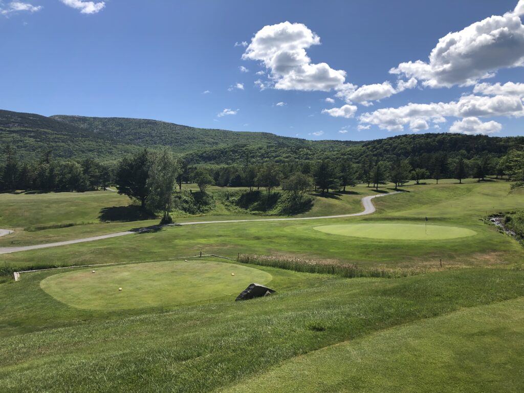 Scenic view of a golf course with lush green fairways and a clear blue sky
